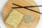 Top view of a wooden tray with chopsticks next to a bowl of instant noodles