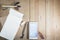 Top view of working object : gray pencil and white smartphone open calculator app on white notebook in wooden background