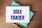 Top view of the written phrase SOLE TRADER, on a wooden background.