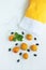 Top view of yellow cotton shopping bag with organic eco apricot fruits on white linen background. Zero waste