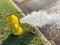 Top view yellow fire hydrant gushing water across a residential street near Dallas, Texas, USA