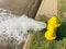 Top view yellow fire hydrant gushing water across a residential street near Dallas, Texas, USA