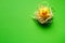 Top view of yellow rubber duck in a straw nest on a green background, minimalistic easter concept or background