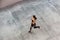 Top view of young attractive athletic woman speed running on city asphalt and workout in the morning time on a sunny summer day.