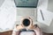 Top view. Young business woman sitting at table with cup of coffee and working on the laptop with graphics and charts