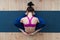 Top view of young Caucasian woman sitting in sleeping tortoise pose supta kurmasana on floor in studio