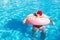 Top view of young drunk guy in christmas hat swim with pink circle in pool. drunk guy on vacation in the hotel