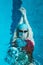 Top view of a young female swimmer training in the pool, swimming on her back underwater. Floats under water and blows