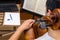 Top view of a young man playing the cello in the middle of an online class with a laptop computer and a notebook on the table with