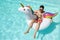 Top view of a young man wearing sunglasses drinking a refreshment on a unicorn inflatable ring in a swimming pool