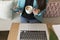 Top view of a young woman writing on laptop keypad. She is sitting in a coffee shop. Modern life of a blogger with mobile phone,