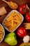top view of ziti pasta in bowl with spaghetti and rotini types in bowl and spoon salt tomato garlic pepper on wooden background