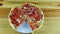 Top view zoom in at sliced pizza with pepperoni, bacon, and vegetables on white plate