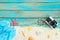 Top viwe of beach sand with slipper, starfish,shells, coral, retro camara and bracelet made of seashells on blue wooden backgroun