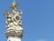 Top of a white baroque column with statues of saints to Budapest in Hungary.