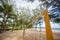 Top of yellow voleyball net on beach among palm trees