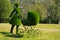 Topiary sculpture of mother with for a baby made of artificial grass. Figure of female walking with her newborn child