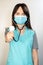 The topic of coronavirus and safety. Young female doctor in a surgical suit on a light background with a stethoscope. Vertical