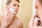 Topless man applying mean of shaving on face