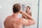 Topless muscle man brushing his teeth front of mirror