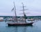 Topsail schooner sitting in a harbor with the children sitting on the bow