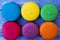 Topshot of sweet and colourful french macaroons on blue wooden background.