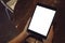 Topview image of hands holding black tablet pc with blank white desktop screen on wooden table