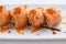 Torched Salmon Maki Sushi with Shrimp Tempura, Avocado and Cheese inside. Topping with Sauce, Ebiko Shrimp Egg and Scallion