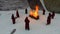 Torchlight procession. Ritual fire. Footage. Group of monks in hood robe walking along winter snow trail in forest