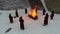Torchlight procession. Ritual fire. Footage. Group of monks in hood robe walking along winter snow trail in forest