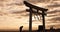 Torii gate, sunset sky in Japan and man in silhouette with clouds, bow and spiritual history on travel adventure. Shinto