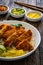 Torikatsu - crispy Japanese chicken cutlet with white rice and marinated vegetables on wooden table