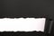 Torn black paper strip white background straight lower edge