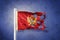 Torn flag of Montenegro flying against grunge background
