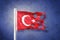 Torn flag of Turkey flying against grunge background