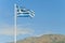 Torn greek flag on flag-post against blue sky
