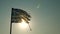 Torn Greek flag waving backlit by summer beach