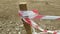 torn red and white warning tape tied to a wooden support flies in the wind.