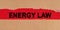 Among the torn sheets of paper on a red background, the inscription - ENERGY LAW