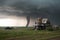 tornado barreling toward farmhouse, with stormchaser in pursuit