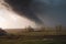 tornado, with debris swirling and flying around it, touching ground in rural area