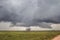 A tornado with no visible funnel touches down on the plains and swirls dust.