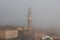 Torre del Mangia in Piazza del Campo and tupical ref roofs of Siena in the thick fog. Tuscany, Italy.