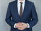 Torso of a businessman standing with hands clenched in middle position in a classic navy blue suit.