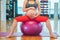 Torso of young pregnant woman in sportswear sitting on purple fitball exercising in gym or at home. Healthy pregnancy