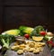 Tortellini Making with vegetales ingredients on rustic kitchen table over dark wooden background