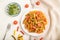 Tortiglioni semolina pasta with tomato and microgreen sprouts on a white wooden background. Top view, close up