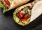 Tortilla wraps with roasted chickpeas falafel patties, fresh vegetables and salad on black stone background. Healthy snack