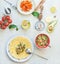 Tortilla wraps sandwiches preparation with tasty fresh avocado tomato salsa salad on white kitchen table background, top view.