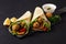 Tortillas wrapped with falafel balls and fresh vegetables, vegetarian healthy food, on a black background, no people,